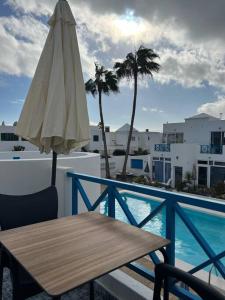 eine Terrasse mit Tisch und Sonnenschirm und ein Pool in der Unterkunft 26 Puerto del Carmen Palm tree in Puerto del Carmen