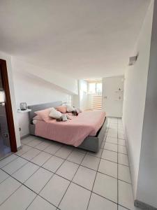 ein Schlafzimmer mit einem rosa Bett in einem weißen Zimmer in der Unterkunft Tramonti In Santa Marinella in Santa Marinella