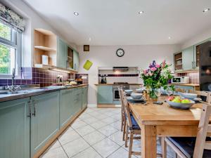 a kitchen with green cabinets and a wooden table at 3 Bed in Brechfa 92116 in Rhyd-cymmerau