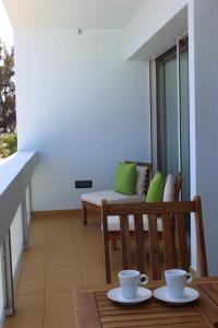 a balcony with a bench and a table with two cups at Mel Apartment in Funchal