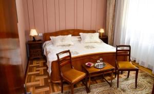 バイレ・ゴボラにあるFormer Ceausescu's Vila Crizantemaのベッドルーム1室(ベッド1台、椅子2脚、テーブル付)