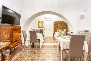 a dining room with tables and chairs and a tv at Terra d'Amuri Hotel Boutique in Catania
