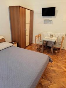 een slaapkamer met een bed en een tafel en een televisie bij Villa Lily in Novi Vinodolski