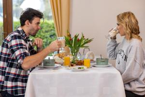 mężczyzna i kobieta siedzący przy stole jedzący jedzenie w obiekcie Piastun SPA&Wellness Krynica-Zdrój w mieście Krynica Zdrój