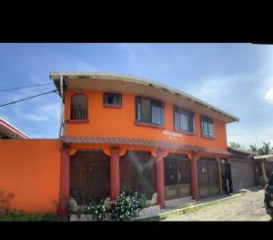 pomarańczowy budynek z płotem przed nim w obiekcie Apartamentos HJJ w mieście Puerto Limón