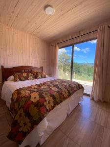 een slaapkamer met een bed en een groot raam bij Cabaña gam.nav in Vichuquén