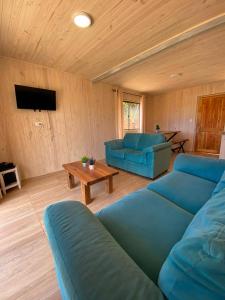 una sala de estar con 2 sofás azules y una mesa. en Cabaña gam.nav, en Vichuquén