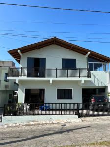 una casa blanca con balcón y un coche en Casa no centro de Garopaba, en Garopaba
