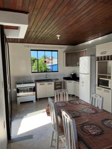 Una cocina con una mesa con sillas y un refrigerador. en Casa no centro de Garopaba, en Garopaba