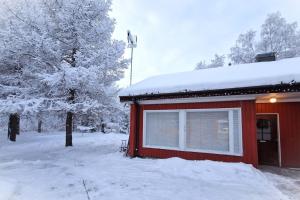 una casa rossa con la neve sopra di Charming house in Kuusamo a Kuusamo