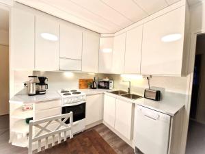 una cocina blanca con armarios blancos y fregadero en Charming house in Kuusamo, en Kuusamo