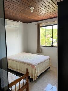 un dormitorio con una cama y una ventana en Casa no centro de Garopaba, en Garopaba