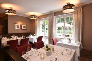 un restaurante con mesas blancas y sillas rojas en Hotel Restaurant Waldesruh en Emstek