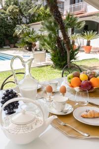 una mesa con platos, tazas y fruta. en Domus Orestea Sicily Luxory Villas in Mondello, en Palermo