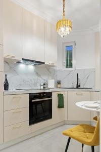 una cocina con armarios blancos y una lámpara de araña en Apartament - Rafinament Arhitectural - Blocul Wilson, en Bucarest