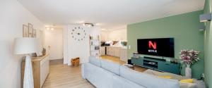 a living room with a blue couch and a tv at FENJOY: Ferienapartment mit Balkon / Zentral / BBQ in Bernau am Chiemsee