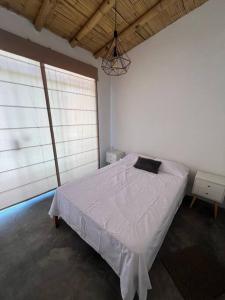 1 dormitorio con 1 cama blanca grande en una habitación con ventanas en La Cabaña de Acapulco - Zorritos -Acapulco-Tumbes en Huacura