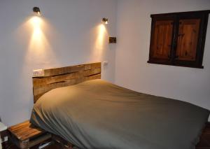 a bedroom with a bed with a wooden headboard and lights at Casa La Sorpresa in La Ermita del Piar