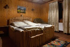 ein Schlafzimmer mit einem großen Bett in einem Holzzimmer in der Unterkunft Файна Чічка in Jaremtsche