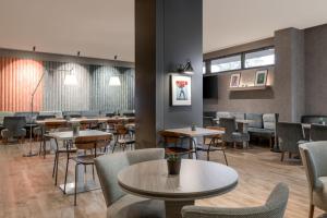 a dining room with tables and chairs and windows at AC Hotel Coslada Aeropuerto by Marriott in Coslada