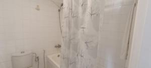 uma casa de banho branca com uma cortina de chuveiro e um WC. em Spacious Apt in Rabat Hay Riad em Rabat
