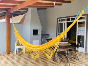 a yellow hammock in a living room with chairs at Casa Barata Próxima a Praia in Bombinhas