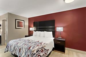 um quarto de hotel com uma cama e uma parede vermelha em Red Roof Inn Redding em Redding
