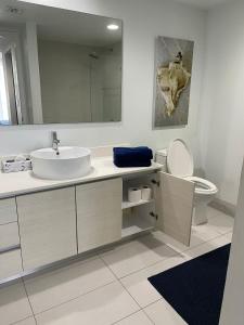 a bathroom with a sink and a toilet and a mirror at Iconic View - Family 2BR Suite - Hotel - Fiber Internet in Hallandale Beach