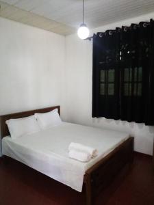 - une chambre avec un lit doté de draps blancs et une fenêtre dans l'établissement Sea Breeze Rest, à Kottagoda