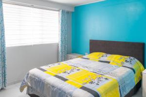 Un dormitorio con una cama con paredes azules y una ventana en departamento moderno en surco., en Lima