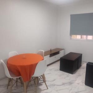 a dining room with a orange table and white chairs at Comfortable apartment in Barrio Norte in Buenos Aires
