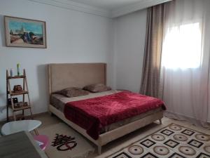 a bedroom with a bed with a red blanket and a window at appartement S+0 in Tunis