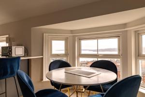 een eetkamer met een tafel, stoelen en ramen bij Seabourne Penthouse Stunning Seaviews with optional hot tub hire at Homesweetholidayhomes in Scarborough