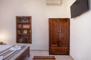 Habitación con armario de madera y TV. en Feneri Traditional House Apt 1- 20' from Elafonisi beach, en Perivólia