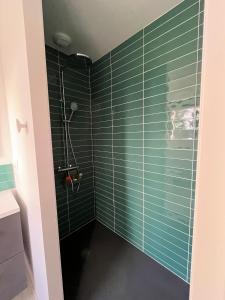 uma casa de banho com paredes em azulejo verde e um chuveiro em Glen Ross, plage à moins de 10 min à pied em Névez