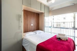 a bedroom with a bed with a red blanket and a window at Ed Marli Santos in Santos