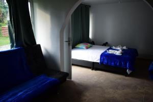 a bedroom with a bed and a chair and a window at Cabaña Maribel encanto in Filandia