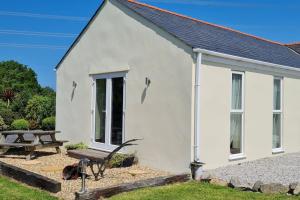a white building with a bench and a picnic table at Romantic rural cottage, log burner, Sky tv early check in ,large gardens in Llangefni