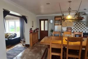 a dining room and living room with a table and chairs at Romantic rural cottage, log burner, Sky tv early check in ,large gardens in Llangefni