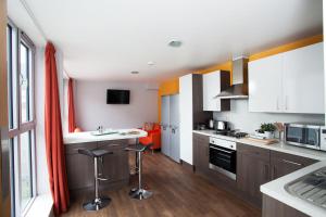 una cocina con armarios blancos y una cocina con taburetes en Unite Students - Sugarhouse Close - Royal Mile, en Edimburgo