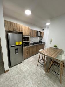 a kitchen with a table and a stainless steel refrigerator at Apartamento Diagonal a Hesperia y Dunas in Naguanagua