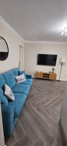 uma sala de estar com um sofá azul e uma televisão de ecrã plano em White rezidence II em Curtea de Argeş