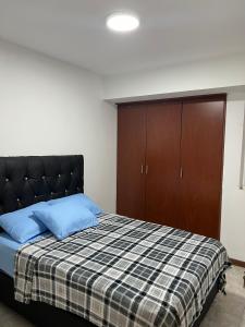a bedroom with a bed with blue pillows and a cabinet at Apartamento Diagonal a Hesperia y Dunas in Naguanagua