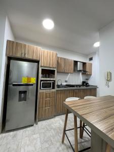 a kitchen with a stainless steel refrigerator and wooden cabinets at Apartamento Diagonal a Hesperia y Dunas in Naguanagua