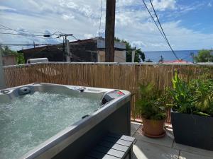 een hot tub op een patio met planten en een hek bij Mémoires des Flots Vue Mer, Jacuzzi, Ville à Pieds in Basse-Terre