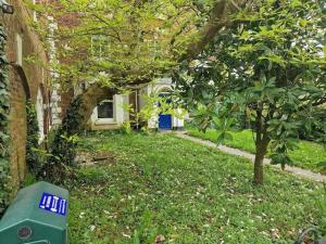 um quintal com uma casa com uma porta azul e uma árvore em Tranquil Studio Apartment em Blandford Forum