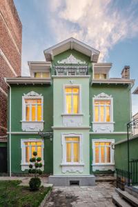 una casa verde con ventanas amarillas y un edificio de ladrillo en Serdika Old City House en Sofía