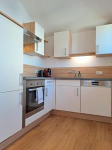 cocina con electrodomésticos blancos y suelo de madera en Sonnseit Appartement, en Sankt Veit im Pongau