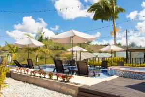 una piscina en un complejo con sillas y sombrillas en Glamping en Guatape Wifi Jacuzzi, en Guatapé