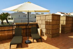 een patio met 2 stoelen en een parasol bij Alquilaencanarias Duplex Playa del Médano in El Médano